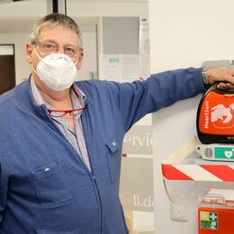 Harald Heinen mit dem Defibrillator, der im Vorraum des Kaller Rathauses hängt. Außerhalb der Rathausöffnungszeiten ist das Gerät derzeit nicht verfügbar.